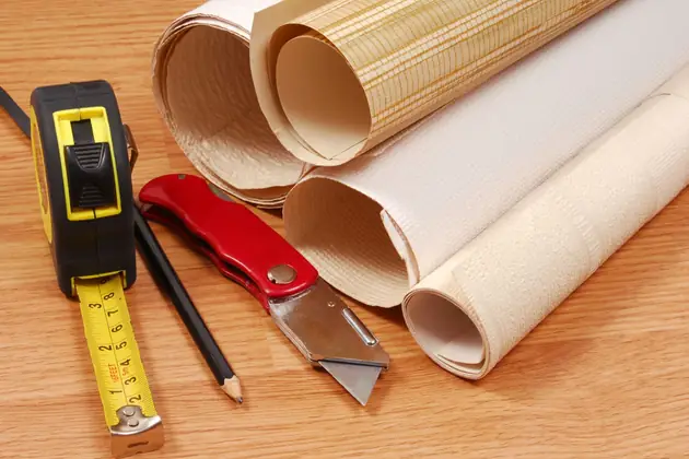 Rolls of wallpaper with a tape measure and craft knife