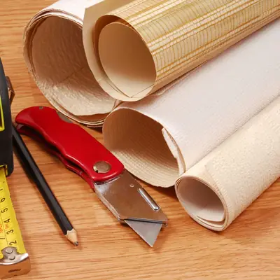 Rolls of wallpaper with a tape measure and craft knife