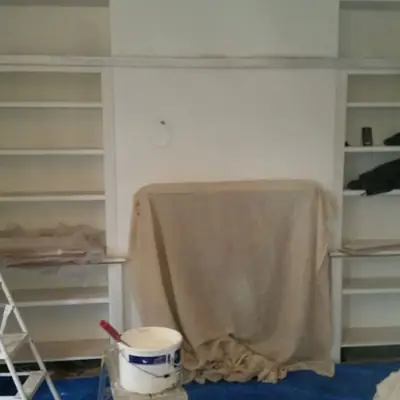 Built-in alcove shelving being painted, with the floor protected